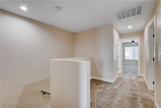 hall featuring baseboards, visible vents, carpet, and an upstairs landing