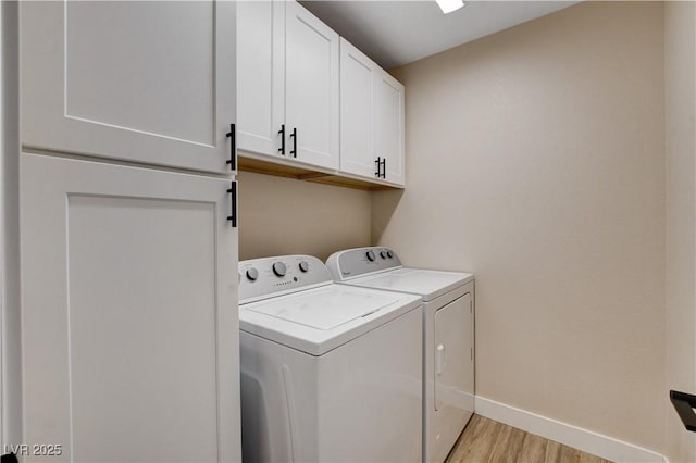 laundry area with light wood-style floors, cabinet space, baseboards, and washing machine and clothes dryer