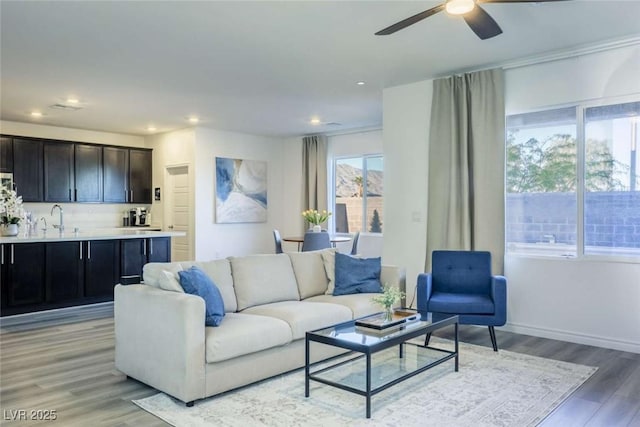 living room with recessed lighting, baseboards, a ceiling fan, and light wood-type flooring