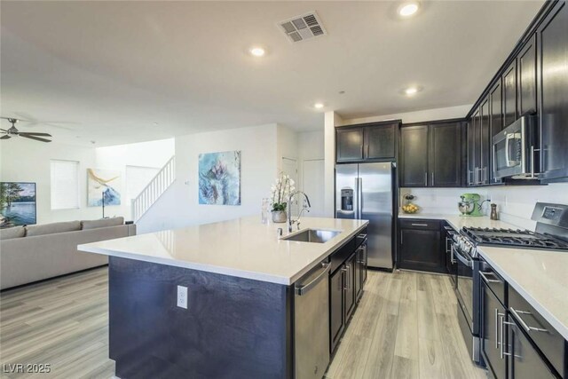 kitchen featuring appliances with stainless steel finishes, a sink, light wood finished floors, a ceiling fan, and visible vents