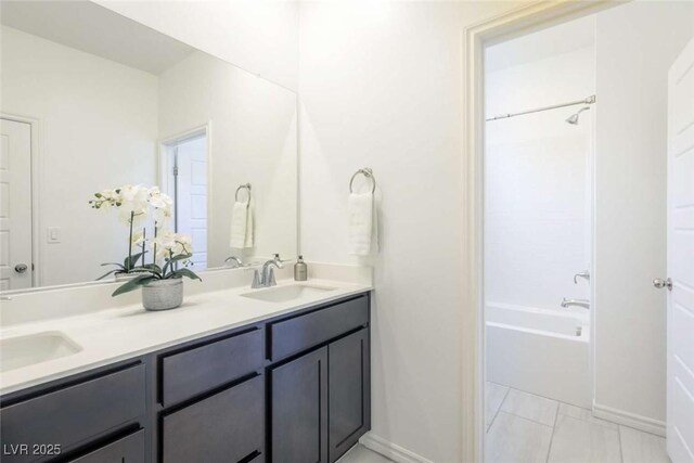 full bathroom featuring double vanity, a sink, shower / bathing tub combination, and baseboards