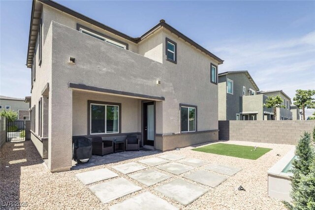 rear view of property with an outdoor hangout area, a fenced backyard, a patio area, and stucco siding