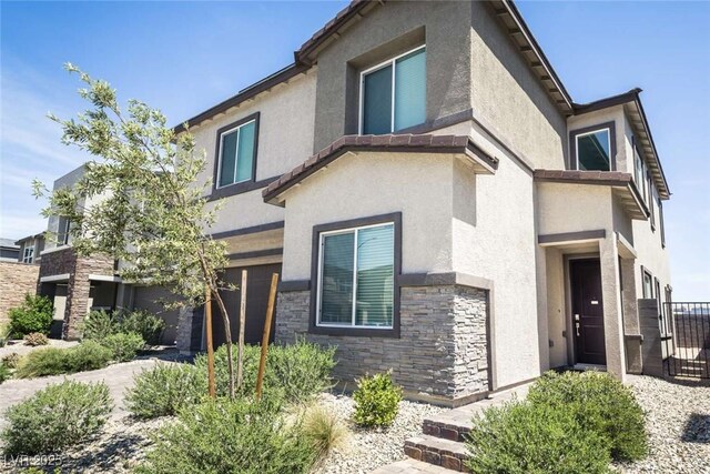 view of front facade with fence, stucco siding, and stone siding