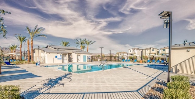 pool with a patio, fence, and a residential view