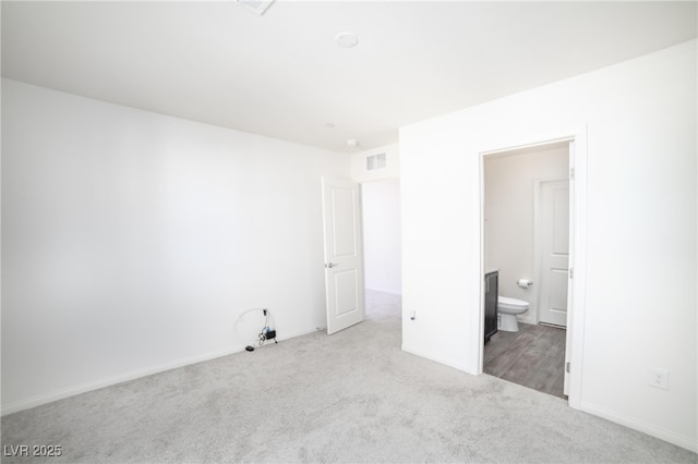 unfurnished bedroom featuring carpet flooring, visible vents, and ensuite bathroom