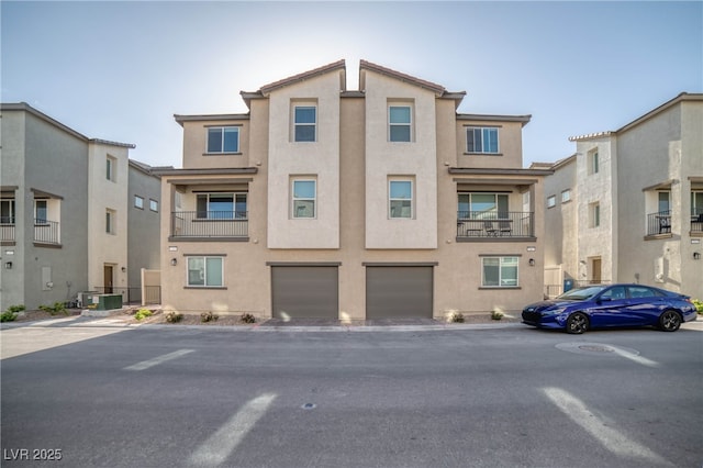 view of front facade featuring a garage, central AC unit, and stucco siding