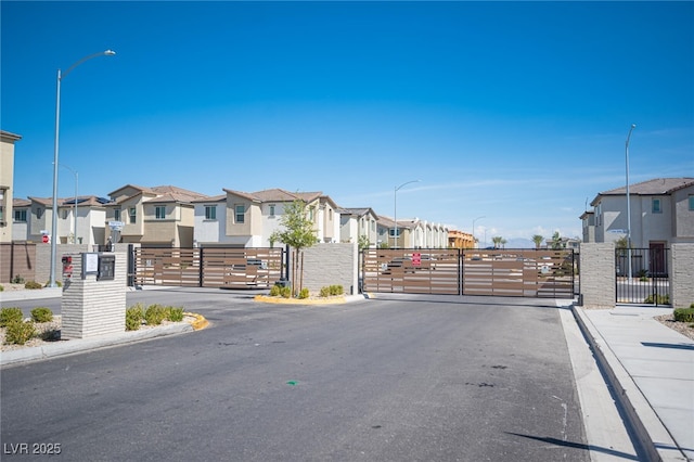 view of street with a residential view, a gate, street lighting, and sidewalks