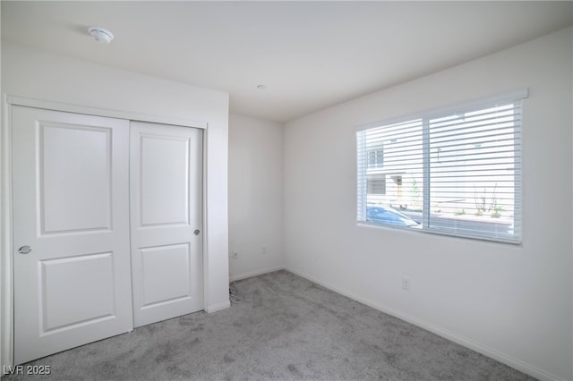 unfurnished bedroom with baseboards, carpet flooring, and a closet