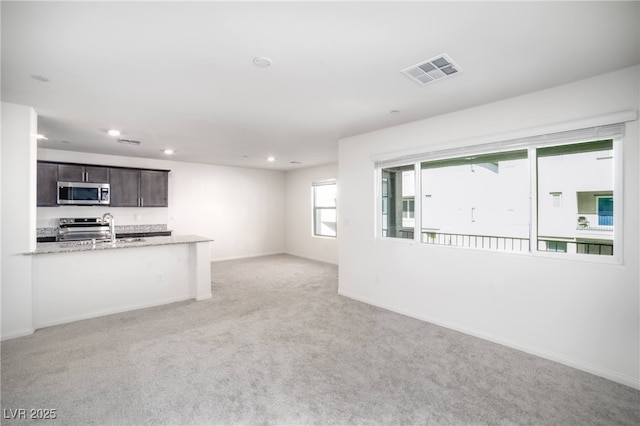 unfurnished living room featuring visible vents, a sink, baseboards, light carpet, and recessed lighting