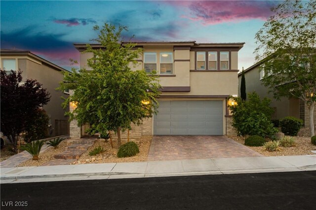 view of front of home featuring an attached garage, decorative driveway, and stucco siding