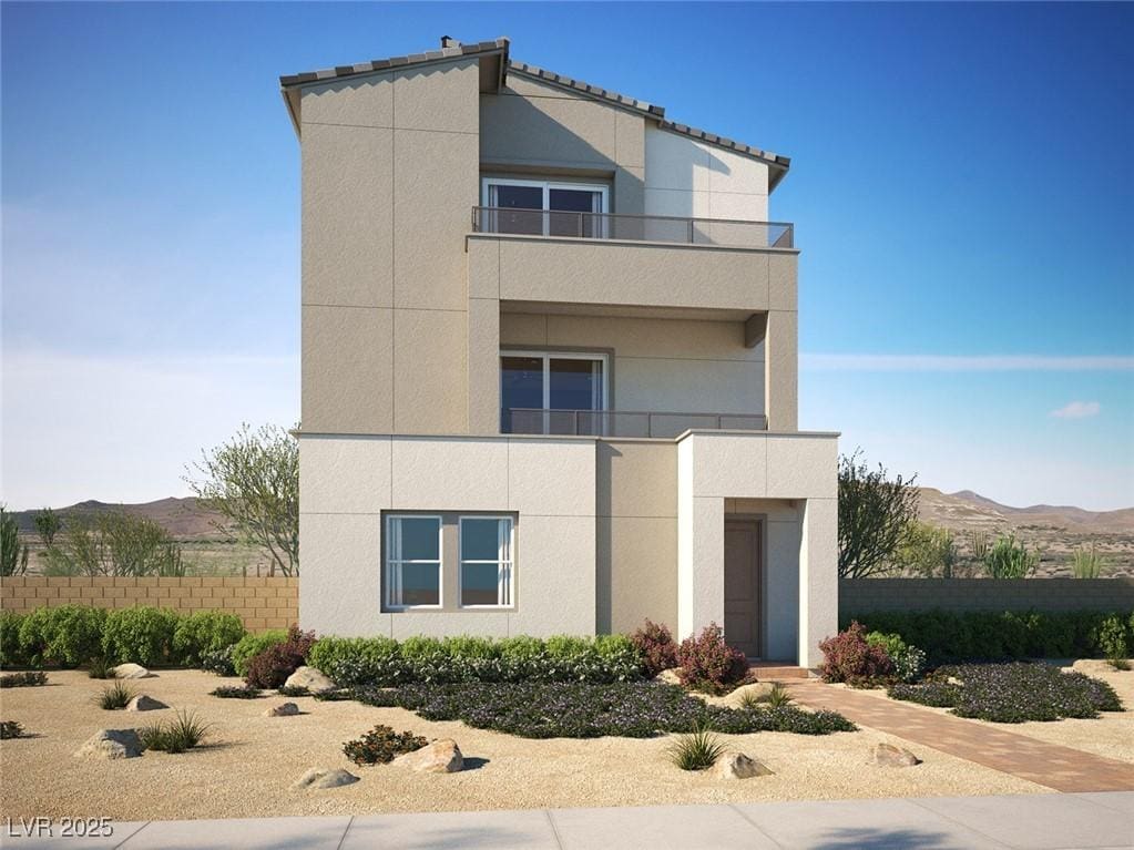 view of front of property featuring fence, a mountain view, stucco siding, and a balcony
