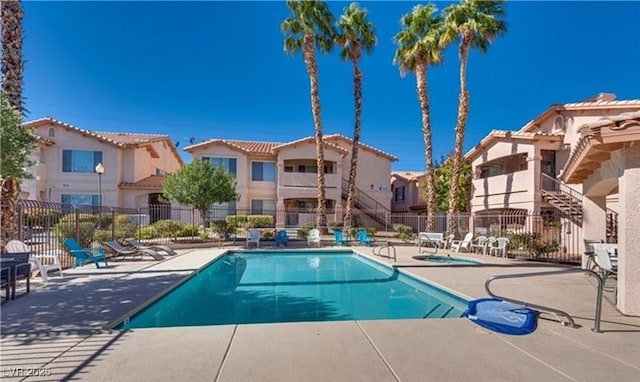 community pool featuring a community hot tub, fence, a patio, stairs, and a residential view