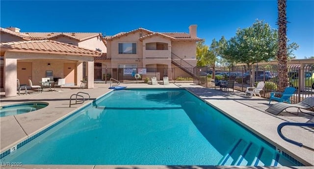 pool with a hot tub, a patio, and fence