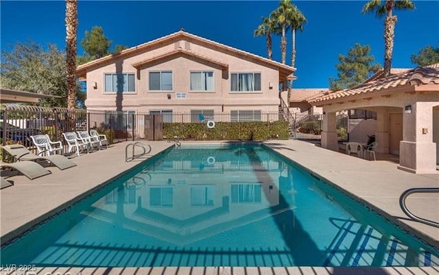 pool with a patio area and fence