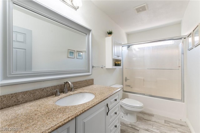 bathroom with vanity, toilet, combined bath / shower with glass door, wood finished floors, and visible vents