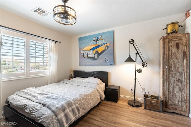 bedroom with baseboards, wood finished floors, and visible vents