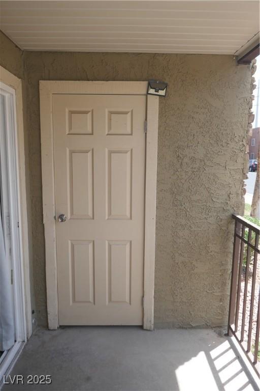doorway to property with a balcony and stucco siding
