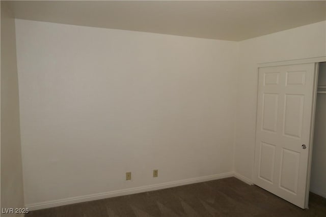 unfurnished room featuring baseboards and dark carpet