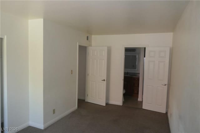 unfurnished bedroom featuring baseboards, dark colored carpet, and visible vents