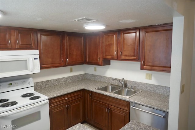 kitchen featuring visible vents, a sink, a textured ceiling, and white appliances
