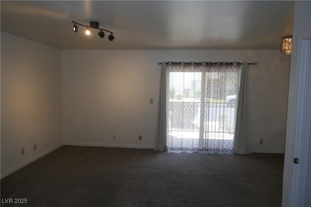 carpeted empty room with baseboards and rail lighting