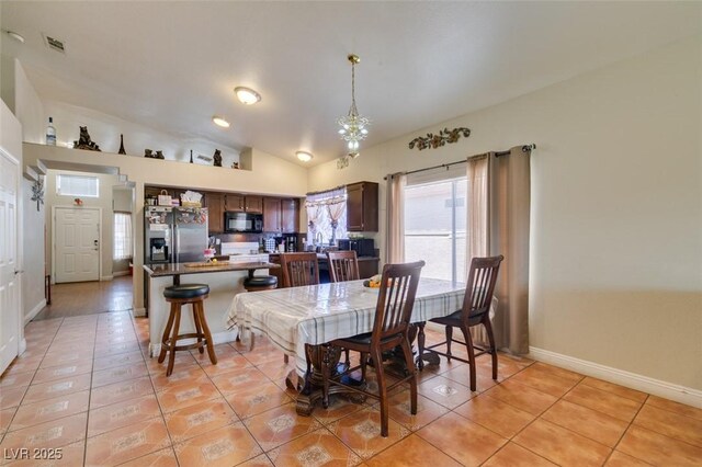 dining area featuring baseboards, a notable chandelier, lofted ceiling, and light tile patterned flooring