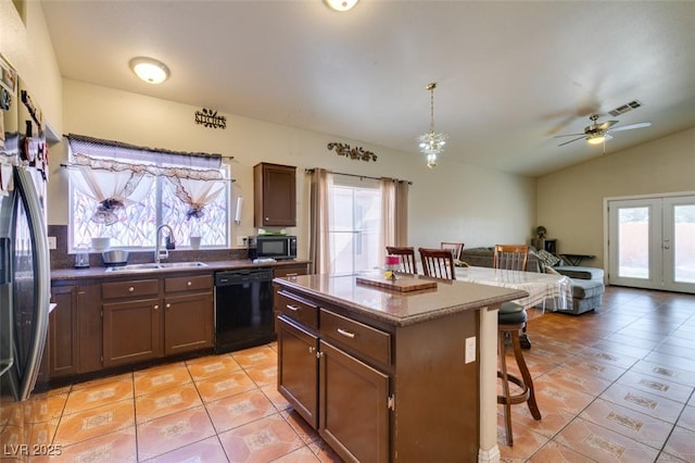 kitchen with a kitchen bar, a sink, light tile patterned floors, black appliances, and open floor plan