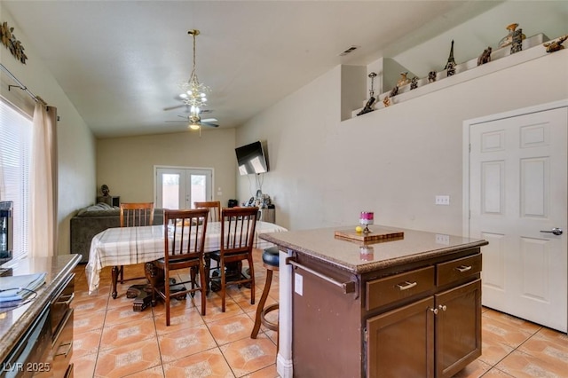 kitchen featuring ceiling fan, a center island, vaulted ceiling, open floor plan, and light tile patterned flooring