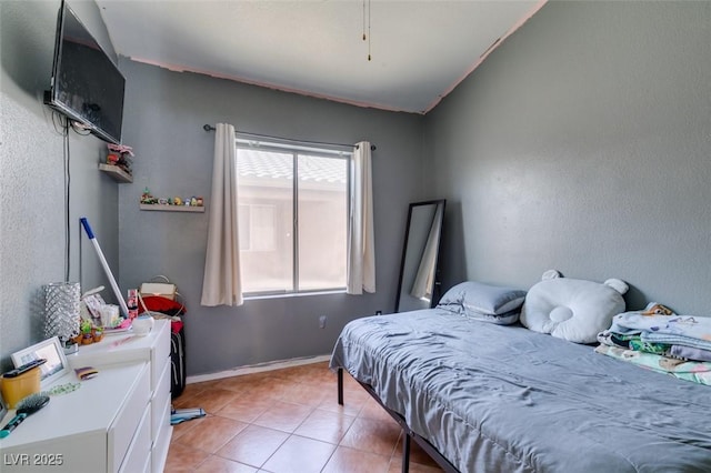bedroom featuring light tile patterned floors and baseboards