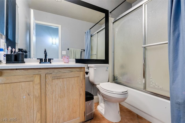 bathroom with toilet, combined bath / shower with glass door, tile patterned flooring, and vanity