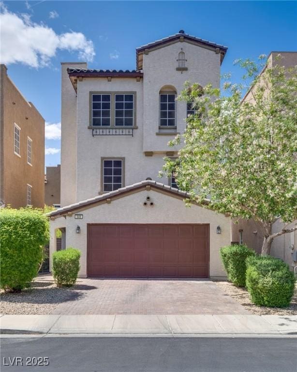 345 Gracious Way, Henderson, NV 89011 - mediterranean / spanish home featuring an attached garage, stucco siding, a tiled roof, and decorative driveway