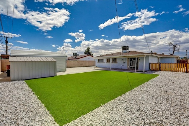 back of property featuring a patio, central AC, an outbuilding, and a fenced backyard