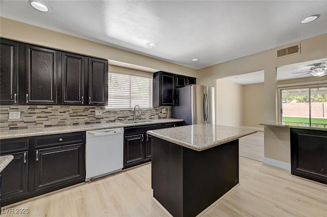 kitchen with visible vents, white dishwasher, light wood-type flooring, freestanding refrigerator, and dark cabinets