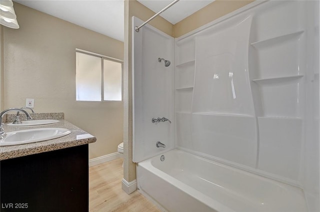full bath with double vanity, shower / bathing tub combination, wood finished floors, a sink, and toilet