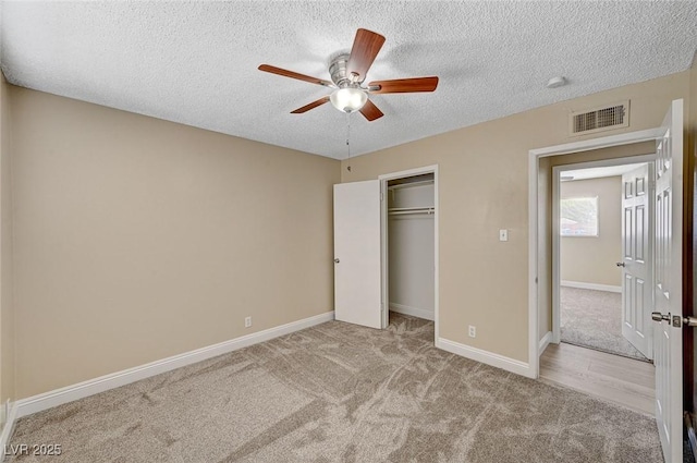 unfurnished bedroom with a textured ceiling, visible vents, baseboards, a closet, and carpet