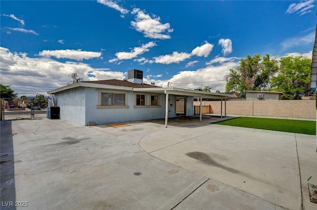 rear view of house with fence, a patio, and stucco siding