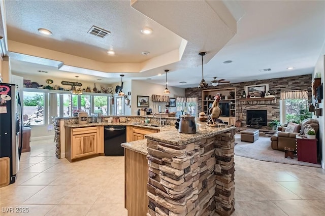 kitchen with visible vents, freestanding refrigerator, light brown cabinets, black dishwasher, and a sink