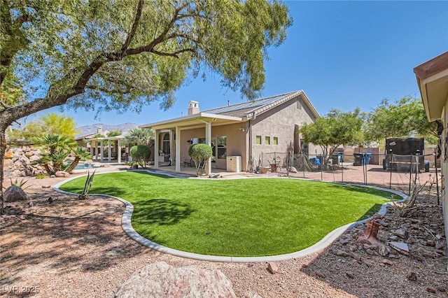 rear view of house with fence, stucco siding, a chimney, a patio area, and a yard