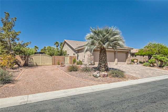 view of front facade with fence, stucco siding, a gate, an attached garage, and driveway