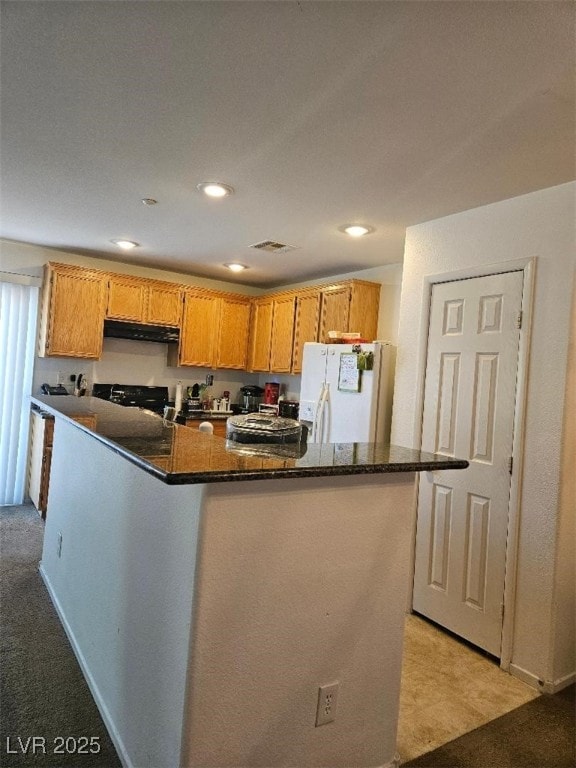 kitchen featuring under cabinet range hood, recessed lighting, light colored carpet, and white refrigerator with ice dispenser