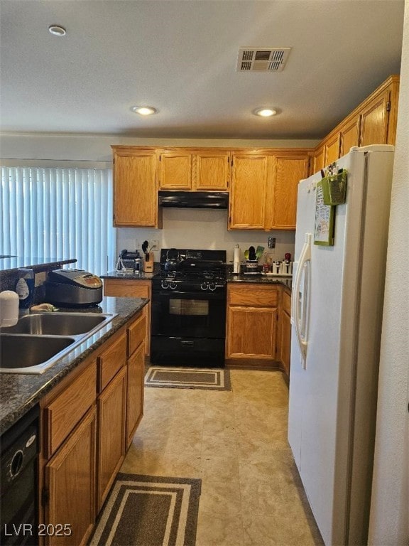 kitchen featuring visible vents, dark countertops, a sink, black appliances, and under cabinet range hood