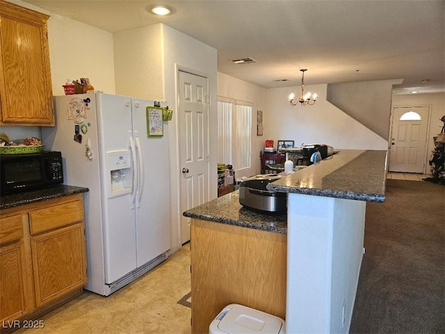kitchen featuring visible vents, brown cabinetry, black microwave, hanging light fixtures, and white fridge with ice dispenser