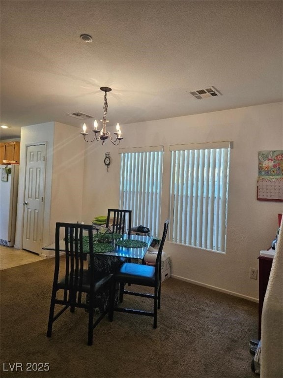 dining space featuring an inviting chandelier, carpet floors, a textured ceiling, and visible vents