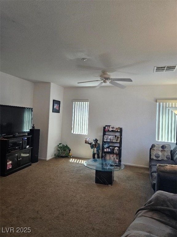 living room featuring carpet floors, a ceiling fan, a textured ceiling, and visible vents