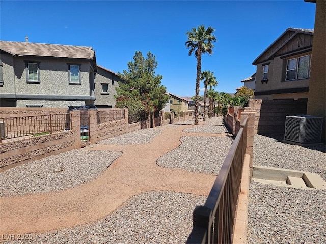 view of yard featuring a residential view, central AC unit, and fence private yard