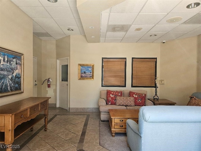 living room with baseboards, a paneled ceiling, and tile patterned flooring