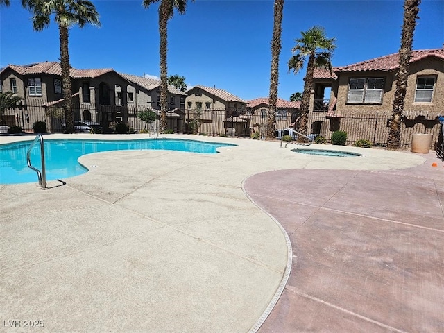 pool featuring fence, a residential view, a community hot tub, and a patio area