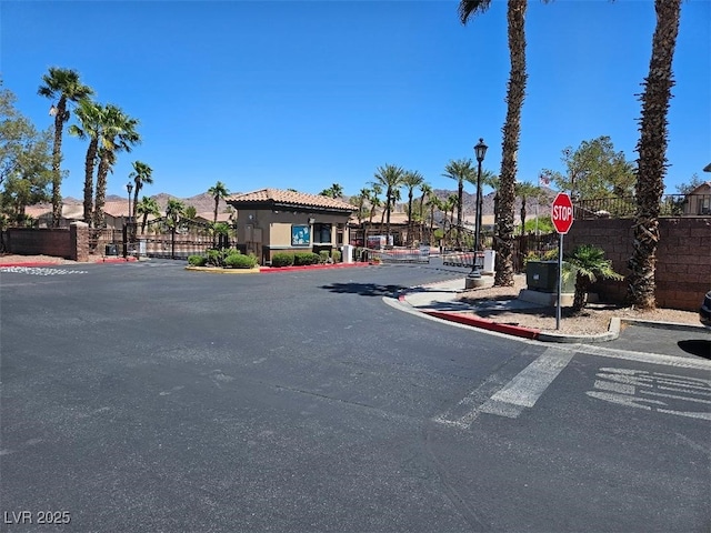 view of street with a gate, traffic signs, curbs, and street lighting