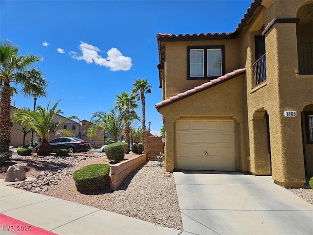 view of side of property featuring an attached garage, driveway, a tile roof, and stucco siding