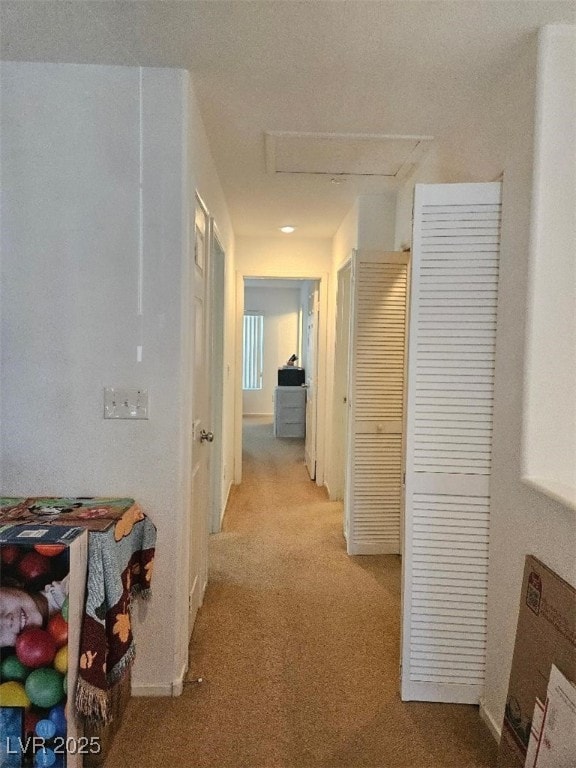 corridor with attic access and light colored carpet
